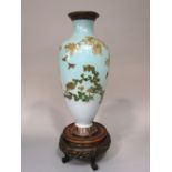 A cloisonné vase of oviform shape with powder blue background showing finches amidst flowering