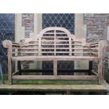 A pair of contemporary Lutyens style teak garden benches with rolled arms, slatted seats, raised