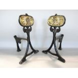A pair of Art Nouveau cast iron andirons on swept supports with embossed brass plate panels