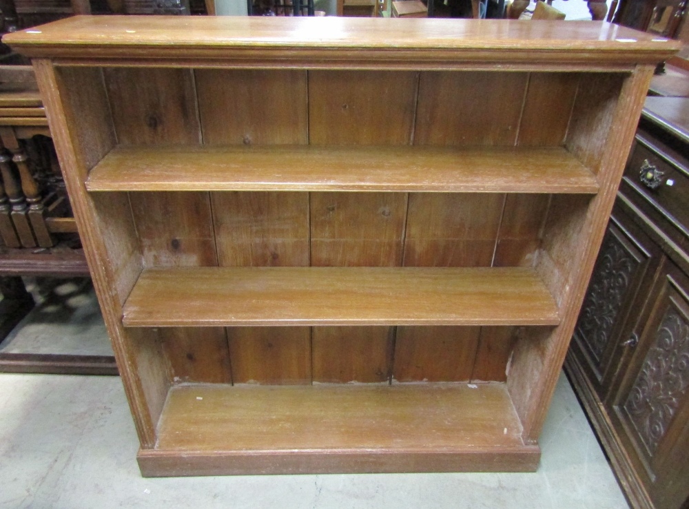 An open oak bookcase with reeded pillar support enclosing two adjustable shelves, 123 cm wide