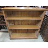 An open oak bookcase with reeded pillar support enclosing two adjustable shelves, 123 cm wide