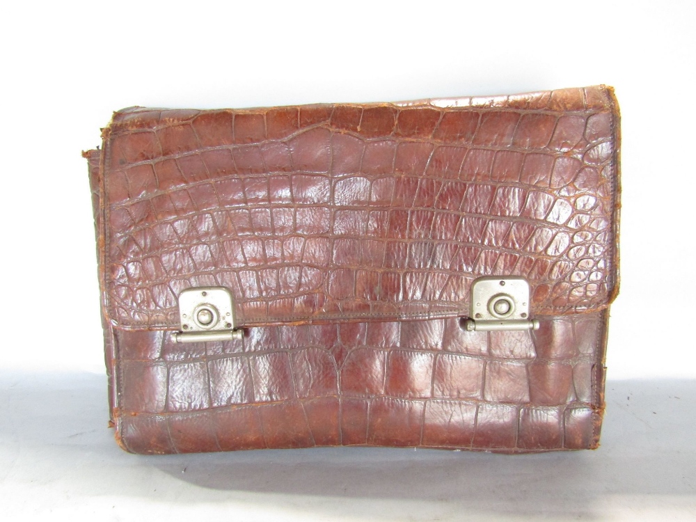 A late 19th century or Edwardian crocodile travelling pouch containing a selection of ivory back