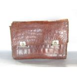 A late 19th century or Edwardian crocodile travelling pouch containing a selection of ivory back