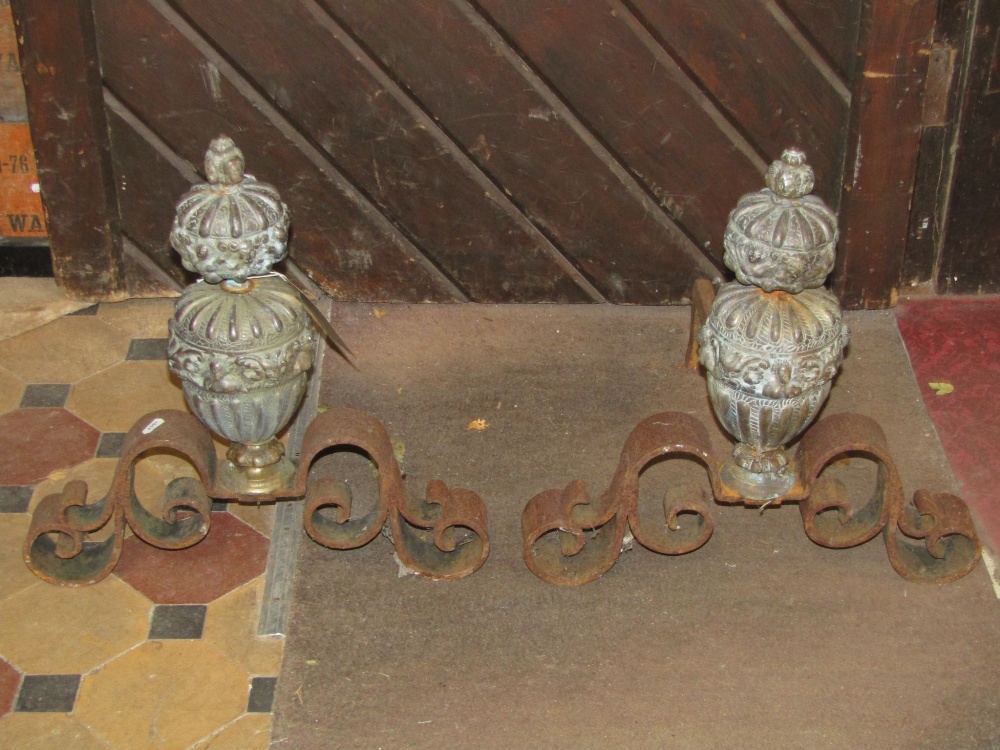 A pair of antique andirons with cast brass baluster shaped stems/finials with repeating mask and