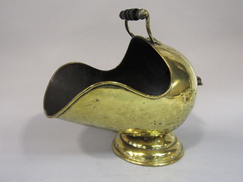 A Victorian brass helmet shaped coal scuttle, with scrolled handles raised on a conical shaped base