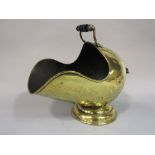 A Victorian brass helmet shaped coal scuttle, with scrolled handles raised on a conical shaped base