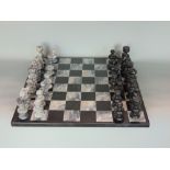 Carved hardstone chess set within a marble chequerboard games board