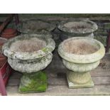 Three weathered cast composition stone garden urns of squat circular form with flared rims, lobed