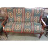 A small Victorian settle with showwood arms and raised on turned supports with later upholstered