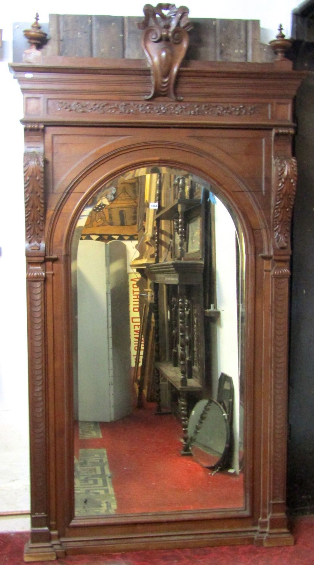 A large 19th century mirror, the walnut frame with moulded and carved detail enclosing an arched