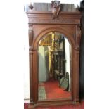 A large 19th century mirror, the walnut frame with moulded and carved detail enclosing an arched