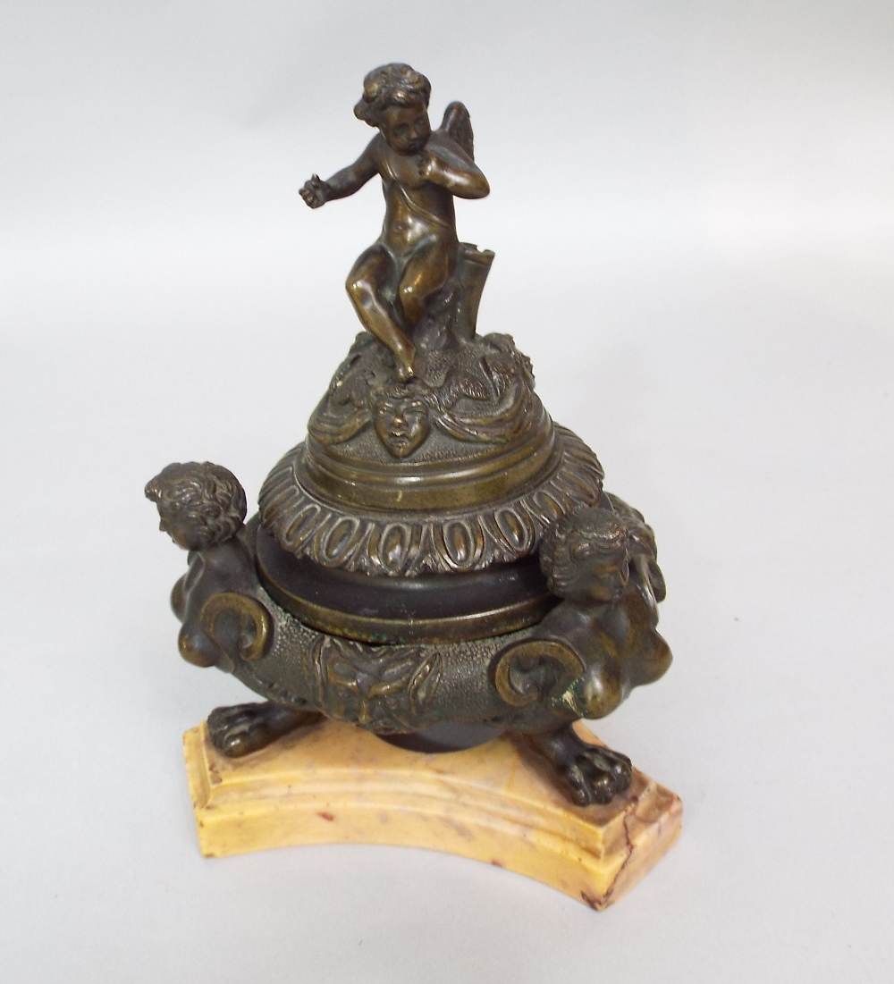 A 19th century Grand Tour bronze inkwell and cover, the finial surmounted by a winged cherub over