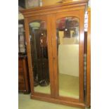 A 19th century satin birch double wardrobe, enclosed by two arched and panelled doors, partially