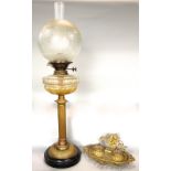 A brass column table standing oil lamp with cut glass font, twin burner and etched glass globe,