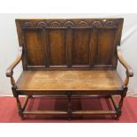 A 18th century style settle, the back incorporating four panels, set beneath a carved frieze, with