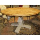 A Nordic style dining table, the circular scrubbed oak top raised on a central square cut baluster