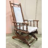 A late 19th century American rocking chair with simple upholstered seat and padded back within a