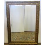 A pair of gilded wall mirrors of rectangular form with repeating scrolled detail with bevelled