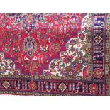 Good quality Persian country house carpet with big central blue medallion and various icons upon a