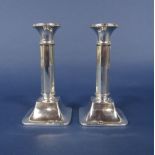 A pair of 1920s silver column candlesticks with faceted stems and swept square bases, maker S &