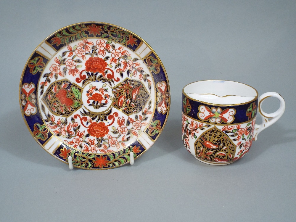 Crown Derby Imari moustache cup and saucer, with panels painted with birds and typical gilt