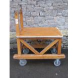 A sturdy ex ministry oak framed trolley with turned handle, flat bed and substantial castors, approx