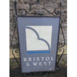 An exterior hanging twin sided Bristol & West sign within a scrollwork frame