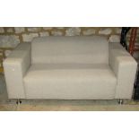 A good quality contemporary two seat sofa with oatmeal ground upholstery, raised on polished tubular