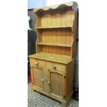 A stripped and waxed pine cottage dresser, the lower section enclosed by two panelled doors and