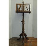 An Edwardian duet music stand in mahogany, with adjustable column, carved detail and tripod base,