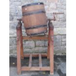 A coopered oak butter churn raised on a pitch pine stand, with splayed supports united by
