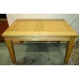 A contemporary light oak pull out extending dining table of rectangular form with single