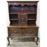 A Victorian oak dresser, the recessed raised back with open shelves surrounding a central cupboard