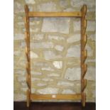 An elm wall mounted gun rack with shaped outline, together with an ashwood high stool with