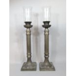 A pair of oversized silver plated storm lanterns/candlesticks of corinthian column form, with