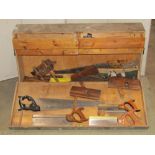 A vintage wooden portable carpenters tool chest and contents to include various planes, saws, etc