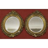 A pair of 19th century gilded mirrors of oval form, with floral trailing borders, 48cm oval