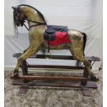 A large Edwardian rocking horse, with dapple finish, later saddlery set on a pine rocker, 130cm high