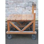 A sturdy ex ministry oak framed trolley with turned handle, flat bed and substantial castors, approx