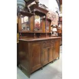 A late Victorian oak mirror backed sideboard, the base enclosed by an arrangement of cupboards and