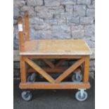 A sturdy ex ministry oak framed trolley with turned handle, flat bed and substantial castors, approx