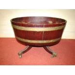 A Georgian mahogany wine cooler, oval brass banded raised on four swept supports with brass cup
