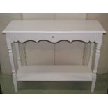 A hall/side table on two tiers, the rectangular top with moulded outline, shaped apron and raised on