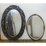 A carved and pierced oak framed wall mirror of oval form with bevelled edge mirror plate and a