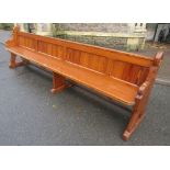 A pitch pine church pew, with plank seat, panelled back and shaped ends with chamfered Gothic