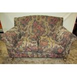 A pair of contemporary but Victorian style two seat sofas with rolled arms, shaped outline and