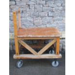 A sturdy ex ministry oak framed trolley with turned handle, flat bed and substantial castors, approx