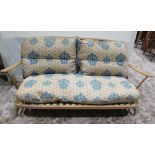 An Ercol light beechwood three piece lounge suite comprising a low three seat sofa with hoop and