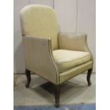 An armchair with shaped outline, arched back, upholstered finish with studded detail raised on