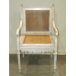 A commode chair with painted frame, down swept and scrolled arms, hinged cane panelled seat and